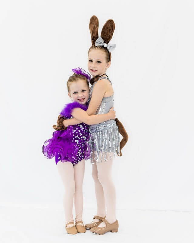 Two Tempo dancers hugging in recital costumes