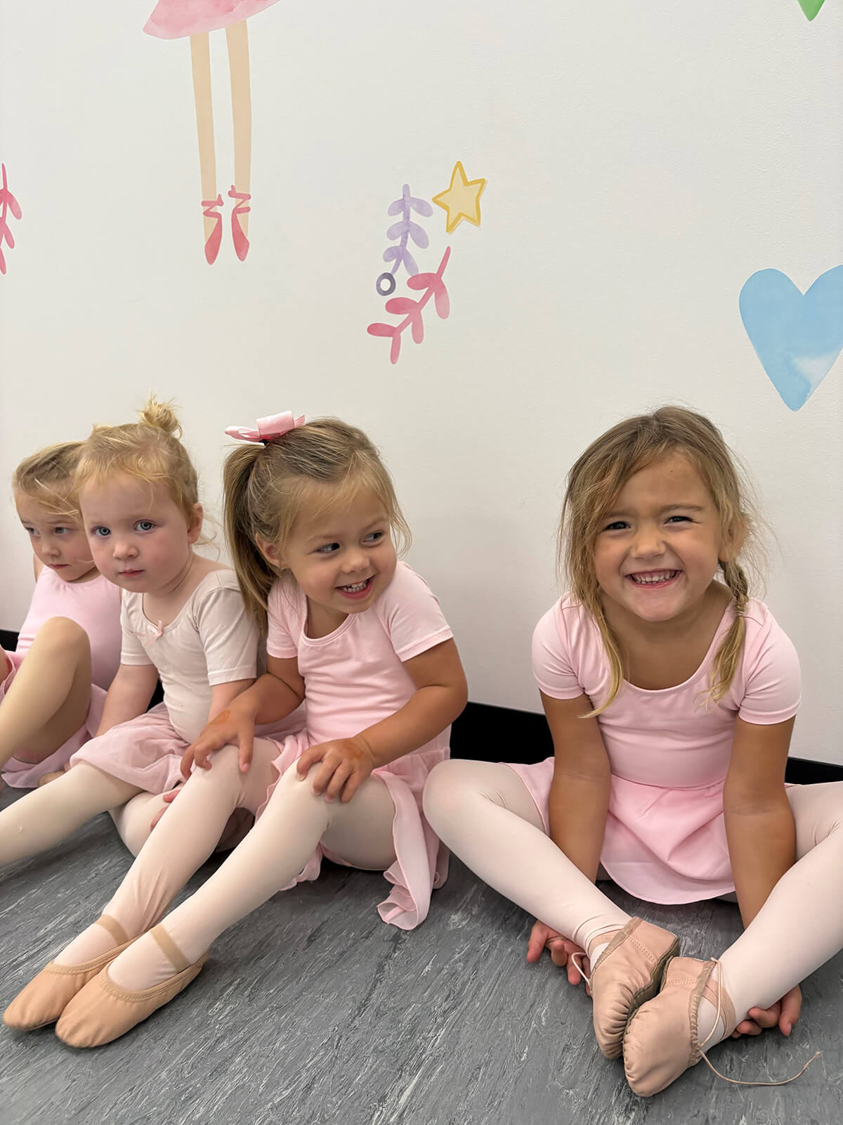 Toddler ballet students in pink leotards smiling during an early childhood dance class in Oxford, MS